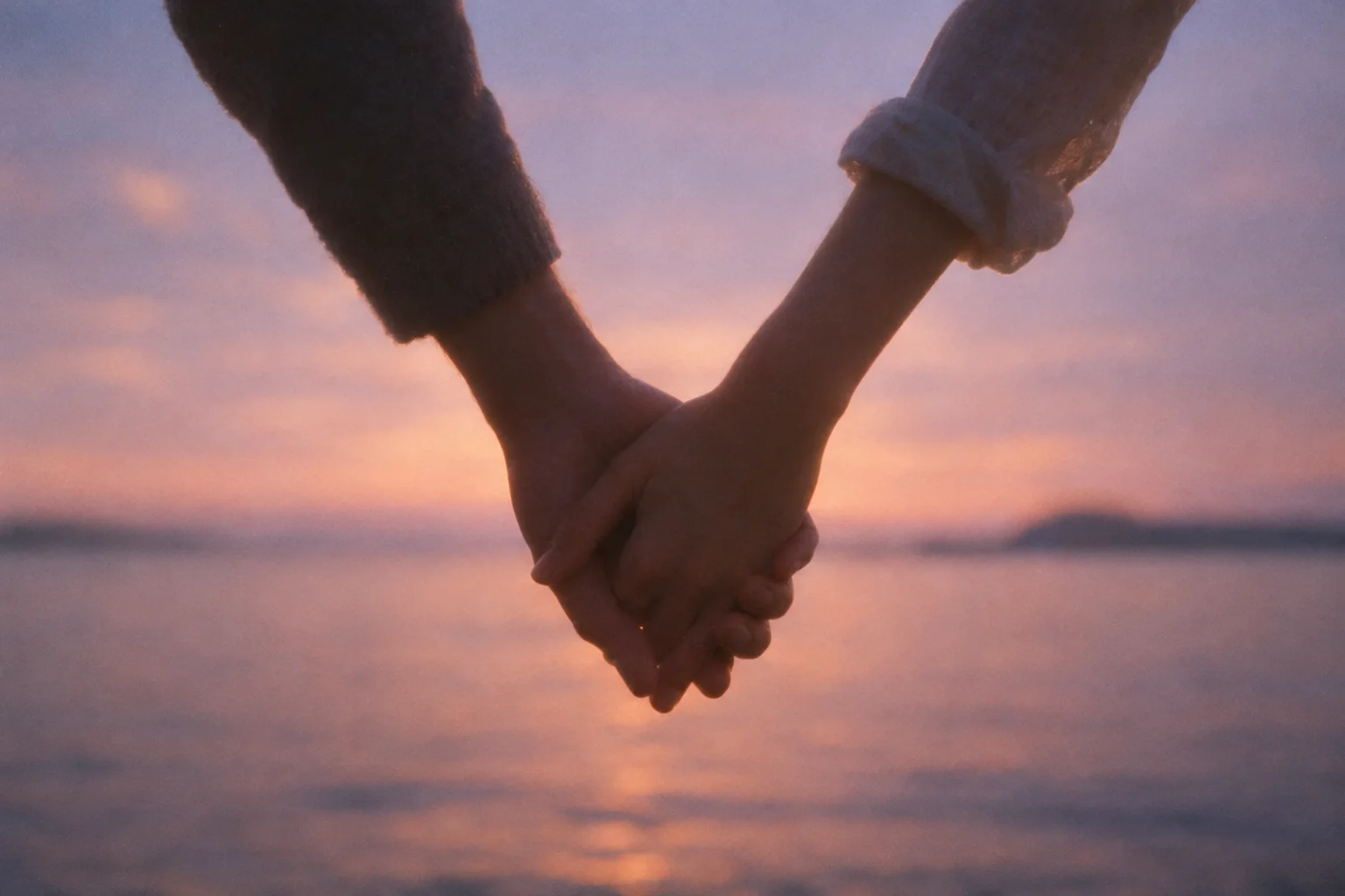A couple holding hands by the water at dusk